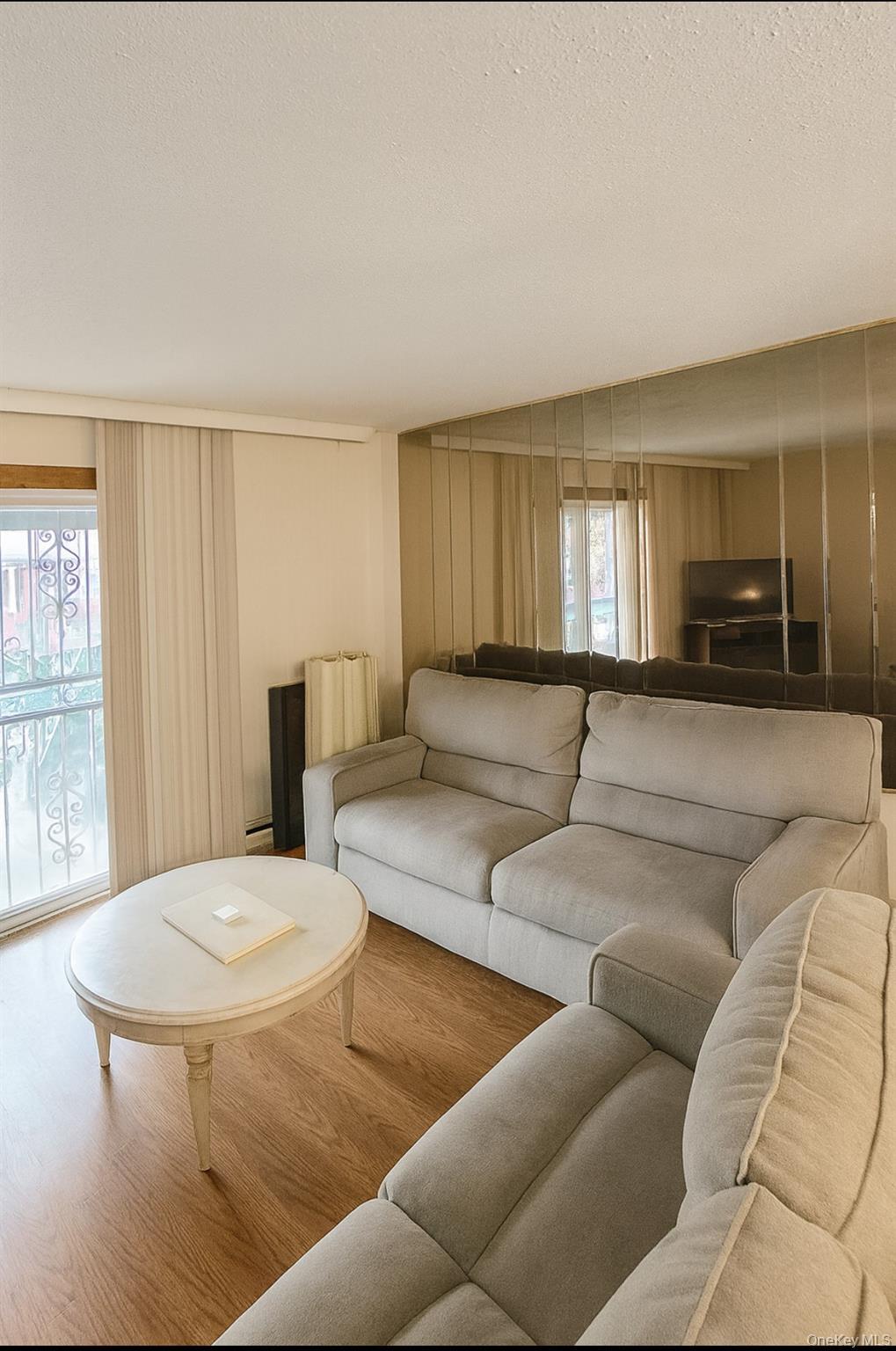 Living area with plenty of natural light, wood finished floors, a textured ceiling, and radiator heating unit