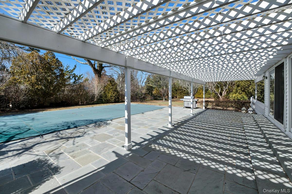 Patio flanking great room with glass slider access to interior. View of patio featuring grilling area and a pergola