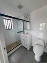 Bathroom with tile walls, a shower stall, and vanity