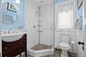 Full bath featuring tile walls, healthy amount of natural light, a wainscoted wall, a shower stall, and vanity