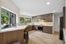 Kitchen featuring light stone counters, stainless steel appliances, tasteful backsplash, modern cabinets, and light wood-type flooring