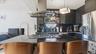 Kitchen featuring a breakfast bar area, island range hood, dark stone counters, backsplash, and stainless steel appliances