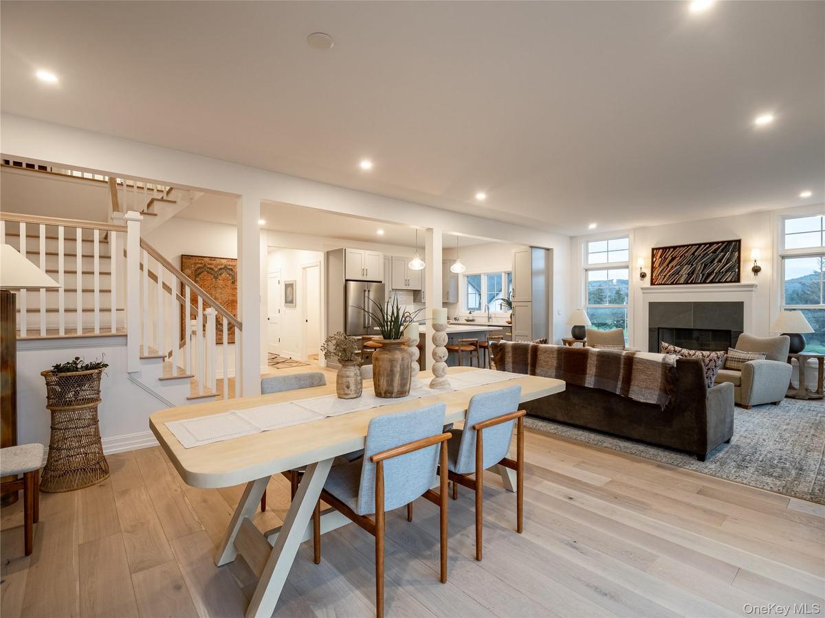 Dining area featuring a tile fireplace, stairs, light wood finished floors, and recessed lighting
