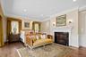Bedroom with ornamental molding, a decorative wall, a wainscoted wall, a fireplace, and dark wood finished floors