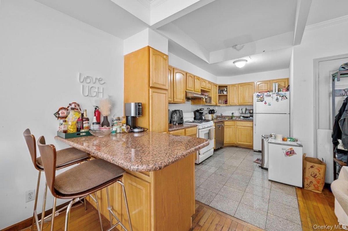 Kitchen with a kitchen breakfast bar, open shelves, light wood-style floors, white appliances, and a peninsula