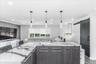 Kitchen island featuring a waterfall-edge countertop with prominent veining, wood-finish cabinetry, and three pendant lights