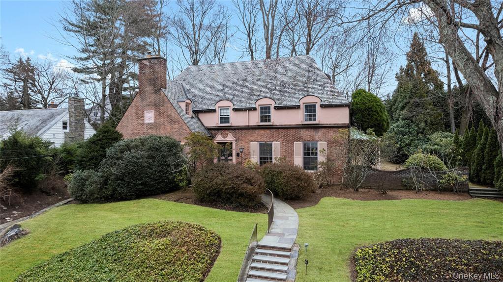 View of front of property featuring a chimney, a high end roof, stucco siding, brick siding, and a front yard