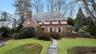 View of front of property featuring a chimney, a high end roof, stucco siding, brick siding, and a front yard