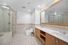 Bathroom featuring tile walls, double vanity, a stall shower, toilet, and a bathtub