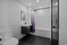 Bathroom featuring a wainscoted wall, tile walls, dark tile patterned floors, vanity, and shower / bathtub combination with curtain