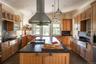 Kitchen featuring decorative backsplash, island exhaust hood, brown cabinetry, a kitchen island, and ornamental molding