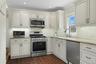 Kitchen with appliances with stainless steel finishes, wood tiled floors, light stone countertops, tasteful backsplash, and ornamental molding