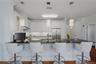 Alternate view of the kitchen, showcasing elegant pendant lighting, stainless steel appliances, and seating for four at the breakfast bar.