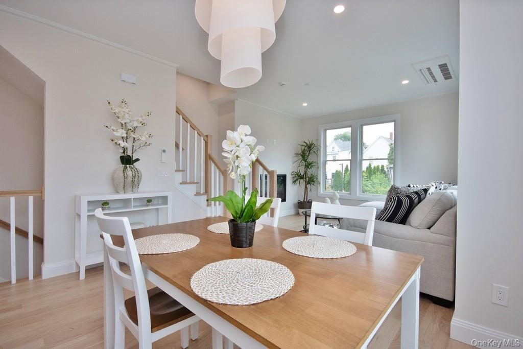 Dining room with stairs, light wood-type flooring, and recessed lighting