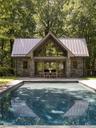 Swimming pool featuring an exterior structure, an outdoor structure, a patio, and view of scattered trees