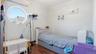 Bedroom featuring dark wood finished floors, crown molding, and an AC wall unit