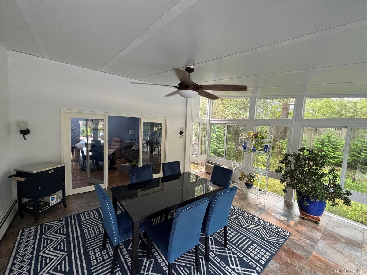 Light-filled Sunroom featuring extensive window-paneled walls, tile flooring, and a ceiling fan with integrated lighting