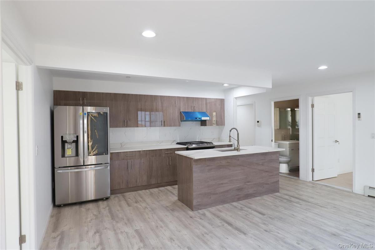Kitchen with stainless steel appliances, light wood-type flooring, under cabinet range hood, modern cabinets, and recessed lighting
