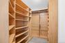 Custom closet system featuring light wood-finish shelving, multiple hanging rods, and integrated shoe storage and dimmable overhead lighting