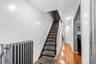 Hallway featuring hardwood flooring, a carpeted staircase with a white spindle banister, recessed lighting, and a cast iron radiator
