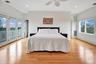 Second Floor Primary Bedroom with stunning ocean and bay surround views, featuring crown molding, light wood-type flooring, access to exterior, a ceil