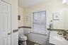 Half bathroom featuring vanity, dark tile patterned floors, a wainscoted wall, and tile walls