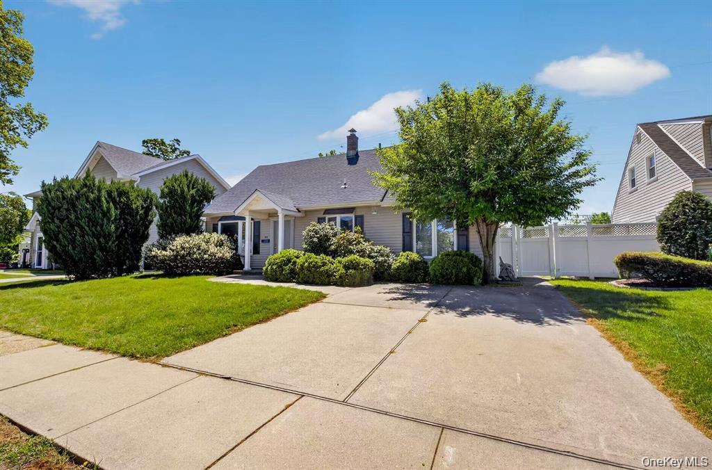 Front exterior with a concrete driveway, established landscaping, and a white privacy fence