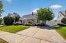 Front exterior with a concrete driveway, established landscaping, and a white privacy fence