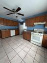 Kitchen featuring wood-finish cabinetry, white appliances, and a tiled floor. Apt. 2