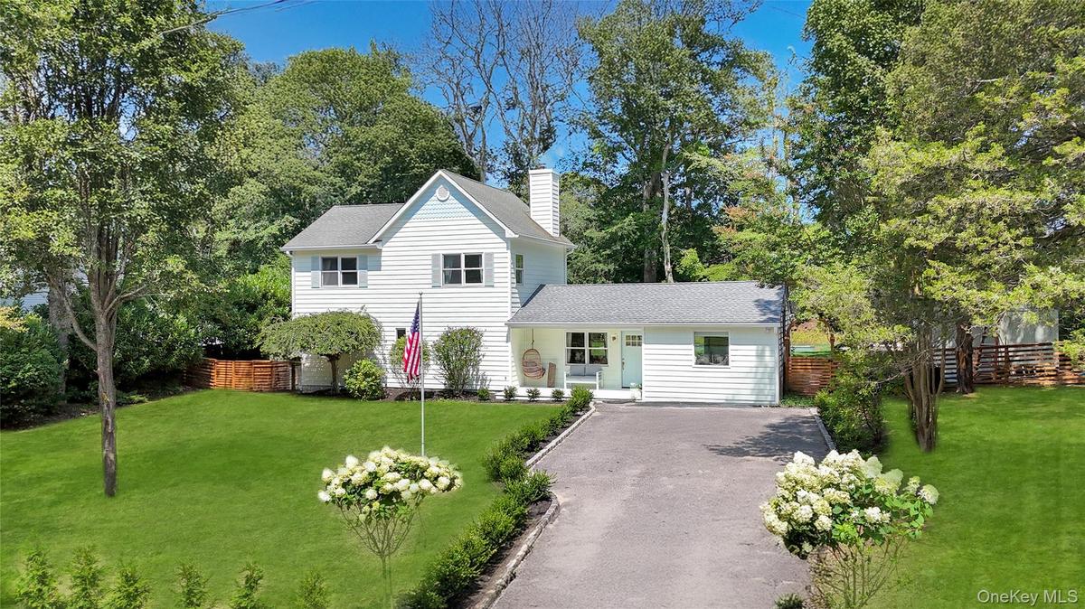 Traditional home with driveway, a chimney, and roof with shingles