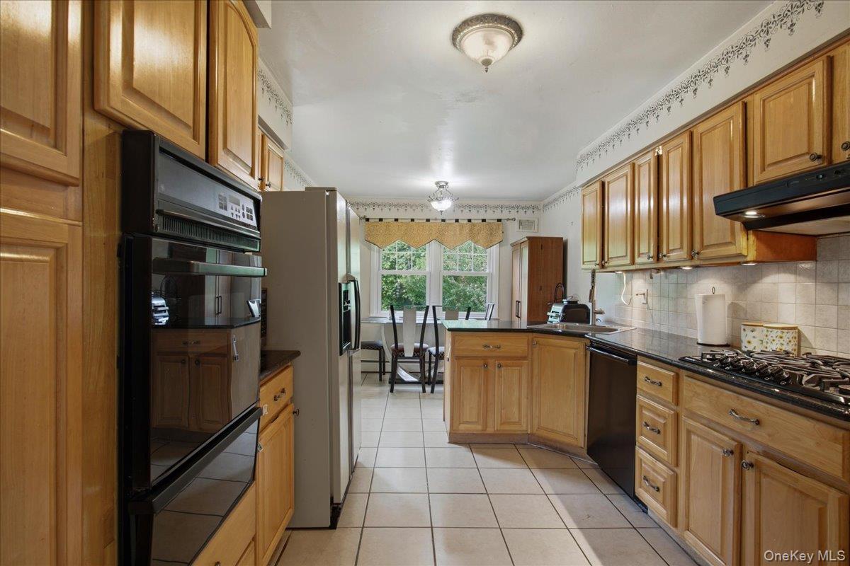 Kitchen featuring wood cabinetry, dark countertops, a built-in double oven, a gas cooktop, and tile flooring
