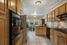 Kitchen featuring wood cabinetry, dark countertops, a built-in double oven, a gas cooktop, and tile flooring