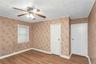 Room featuring wood-finish flooring, a ceiling fan with integrated lighting, and two white panel doors