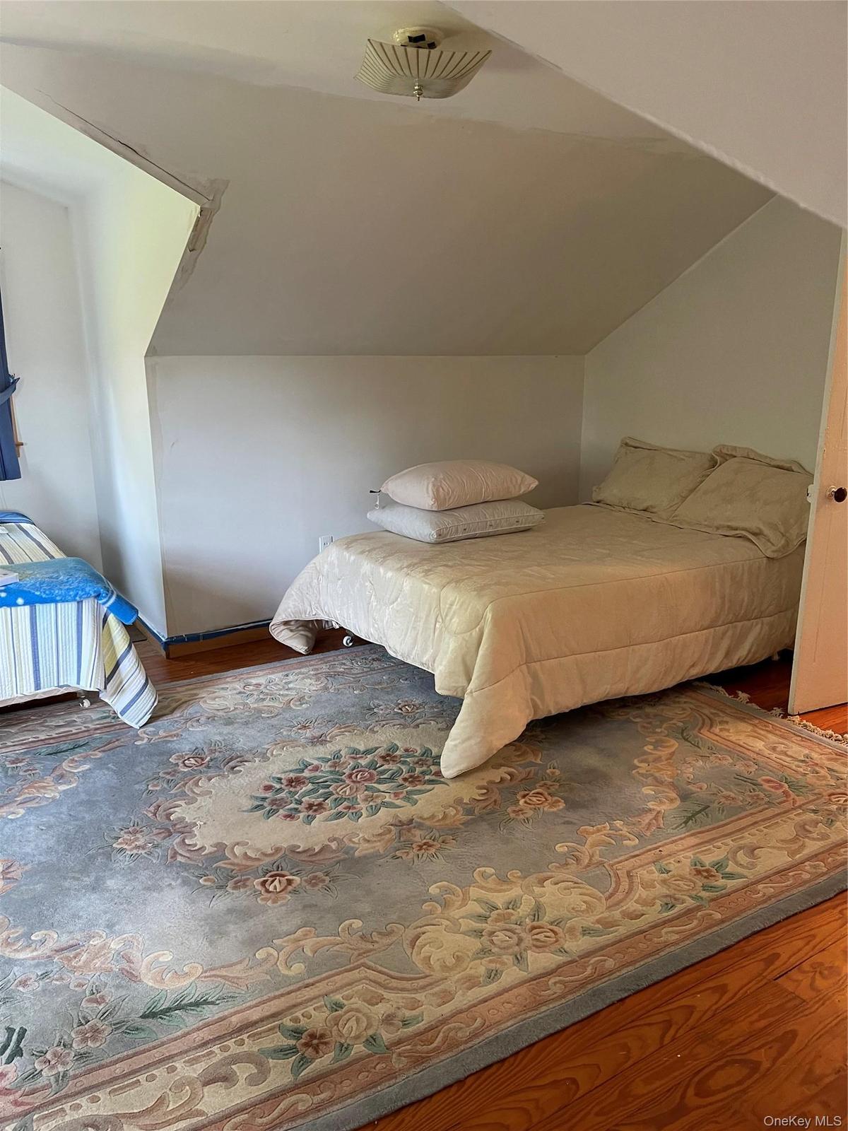 Charming bedroom retreat featuring sloped ceilings and abundant natural light