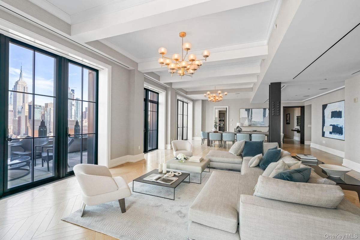 Living area featuring a notable chandelier, baseboards, beamed ceiling, and crown molding
