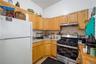 Kitchen featuring a gas range with stainless steel accents, light wood-finish cabinetry, speckled countertops, and a tiled backsplash
