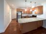 Kitchen featuring a peninsula, recessed lighting, appliances with stainless steel finishes, light stone countertops, and decorative light fixtures