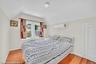 Attic bedroom featuring dormer windows, hardwood flooring, a ceiling-mounted light fixture, and a wall-mounted climate control unit