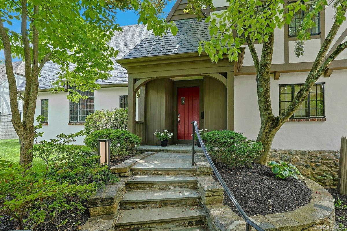 Beautiful stone steps, modern lighting, a wrought iron railing and lush plantings welcome you to this luxurious home, nestled in the heart of Edgemont