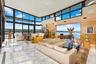 Living room featuring wood walls, a water view, and a high ceiling