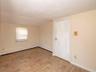 Spare room featuring a baseboard radiator, light wood-style floors, lofted ceiling, and baseboard heating