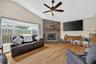 THe family room has a wood burning fireplace, ceiling fan and large picture window