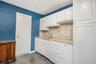 Kitchen with white cabinets, light stone counters, backsplash, and dark tile patterned flooring