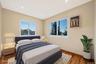 Bedroom featuring wood finished floors, multiple windows, recessed lighting, and an AC wall unit