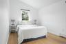 Bedroom with vaulted ceiling, light wood-type flooring, and a baseboard heating unit