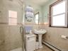 1st Floor Bathroom featuring a glass-enclosed shower, pedestal sink with a chrome faucet, and tiled walls with decorative banding