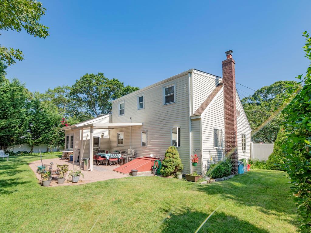 Rear view of house featuring a chimney and a patio
