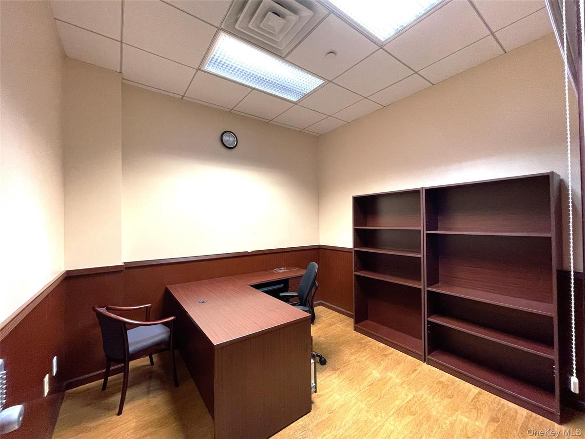 Office space with a wainscoted wall, a drop ceiling, and light wood-style flooring