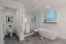 The luxurious primary bathroom exudes spa-like serenity with a sleek, modern design. A private water closet, a freestanding soaking tub serves as the