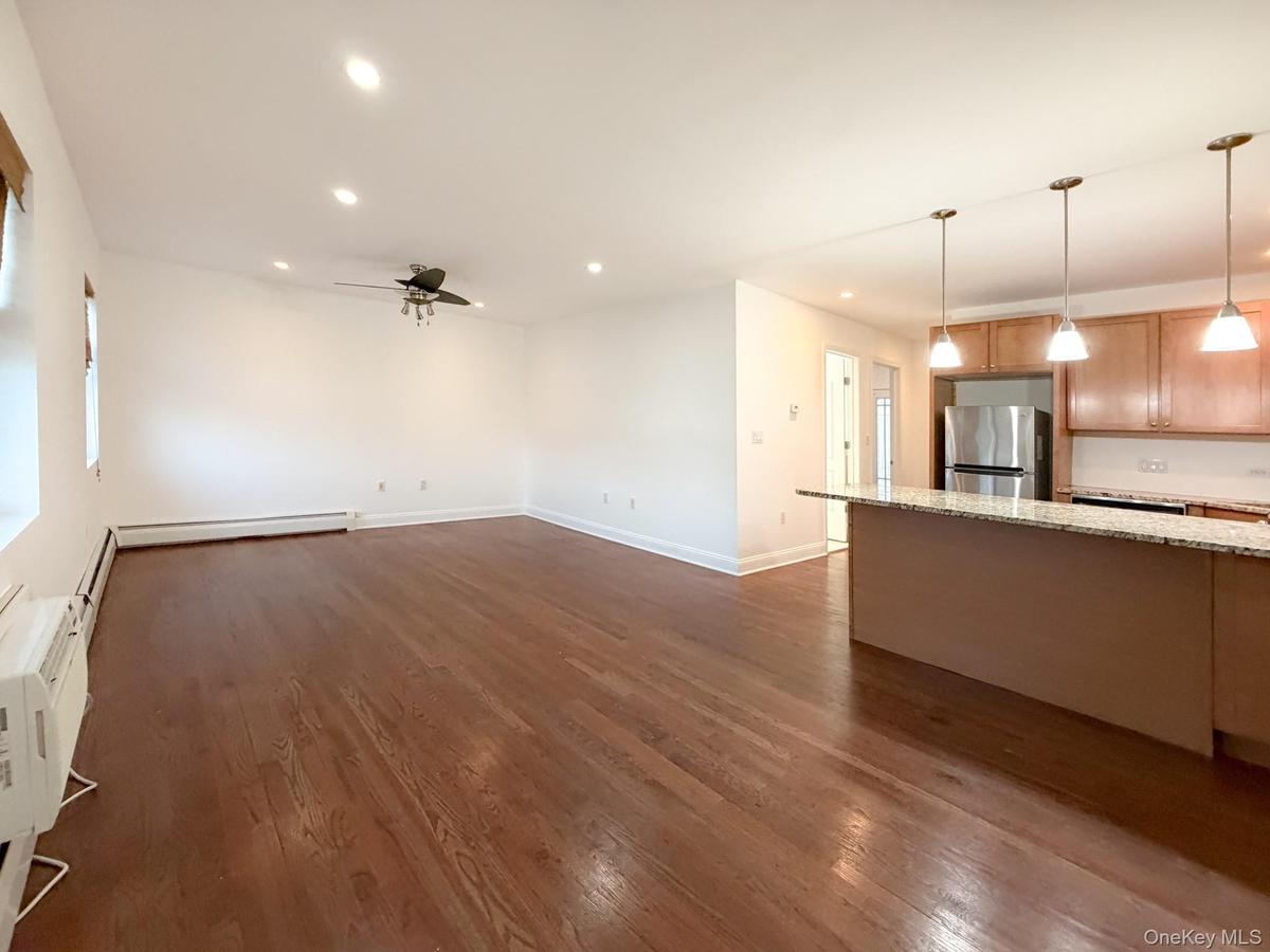 Unfurnished living room featuring recessed lighting, dark wood finished floors, ceiling fan, and an AC wall unit